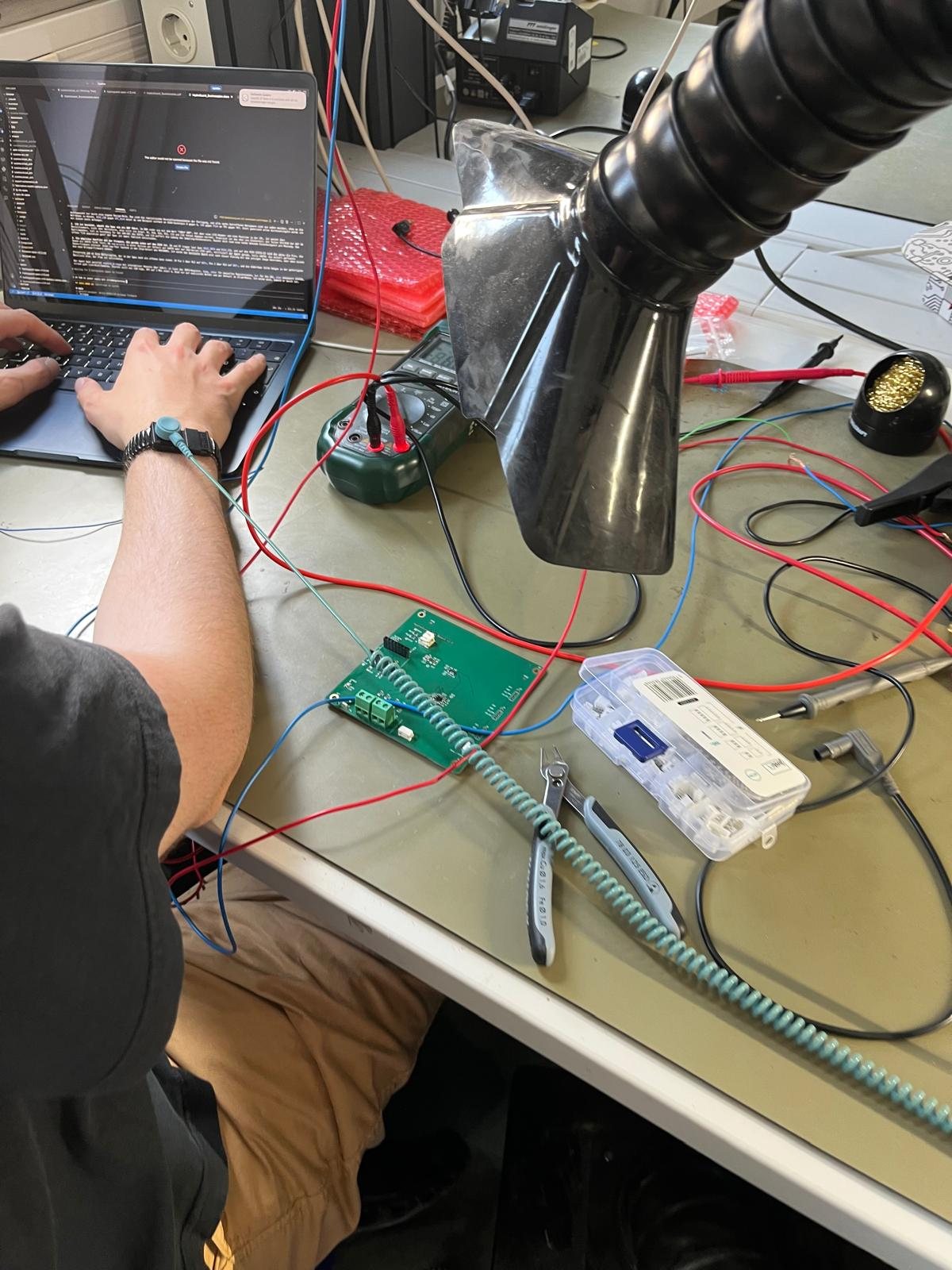 The first prototype on the bench with a multimeter, probes and a laptop